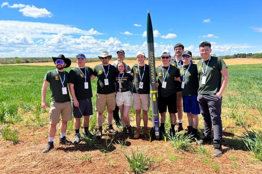 A photo of the rocketry club in a field with one of their projects.